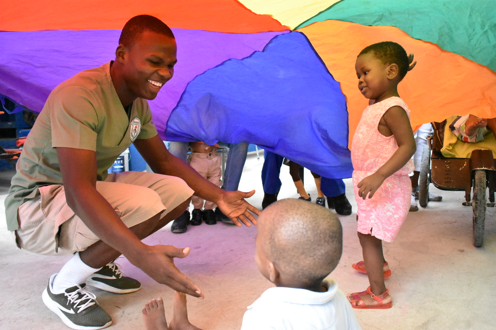 An OT/PT student in Haiti playing with children under a colorful parachute.